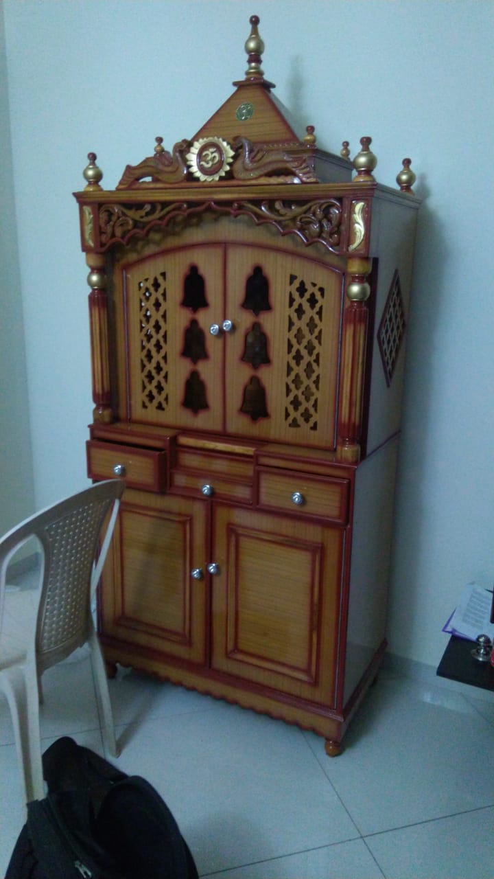 Teak colour pooja mandir with doors and storage in a customer's home
